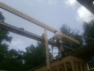 Carpenter setting a ridge beam over a new addition frame — Ice Dam Removal by Roofing Brothers in Highmore