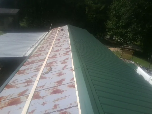 Old rusted panels beside newly installed green metal roofing — Wind Damage Roof Repair by Roofing Brothers in Highmore