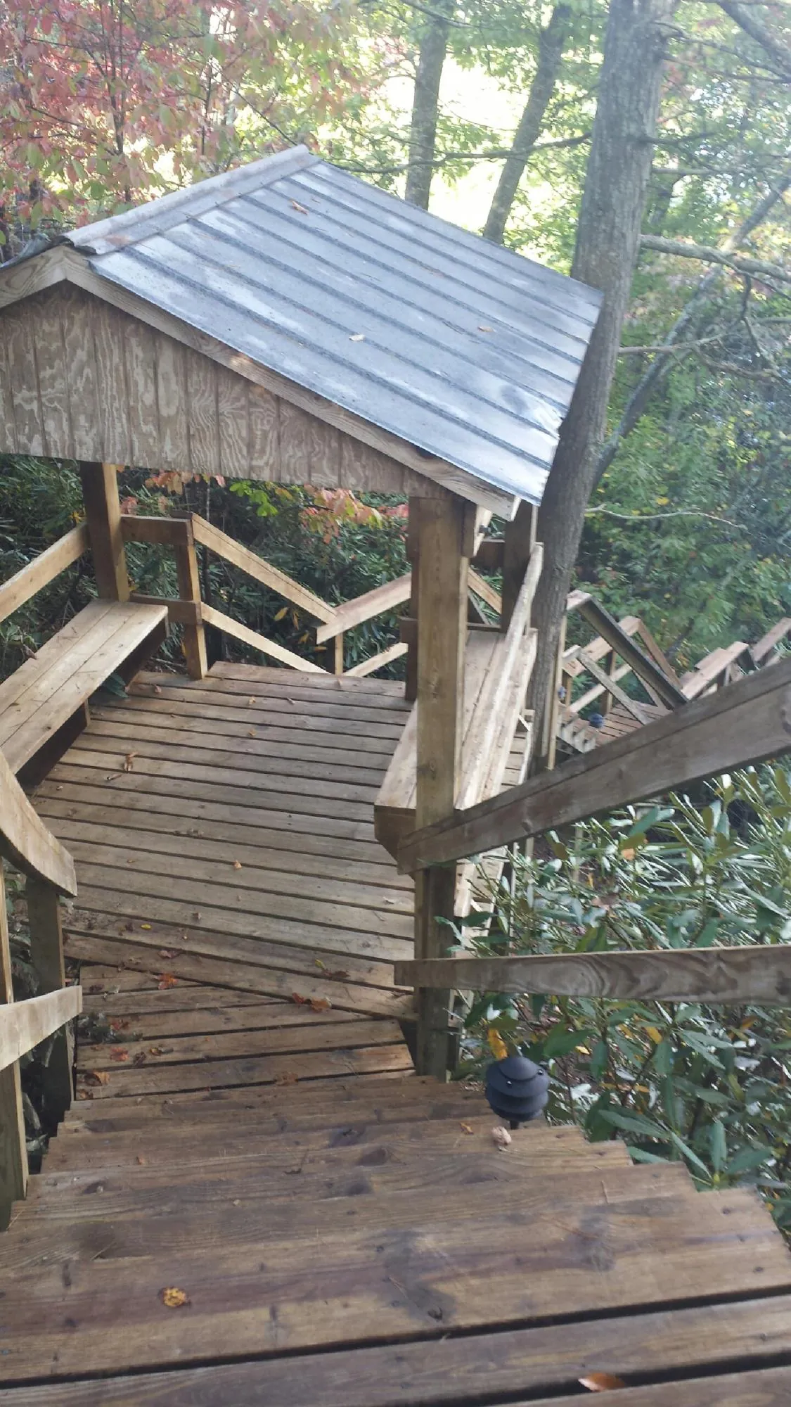 Metal roofed shelter over wooden steps on a wooded walkway — Skylight Repair & Installation work by our crew in Highmore