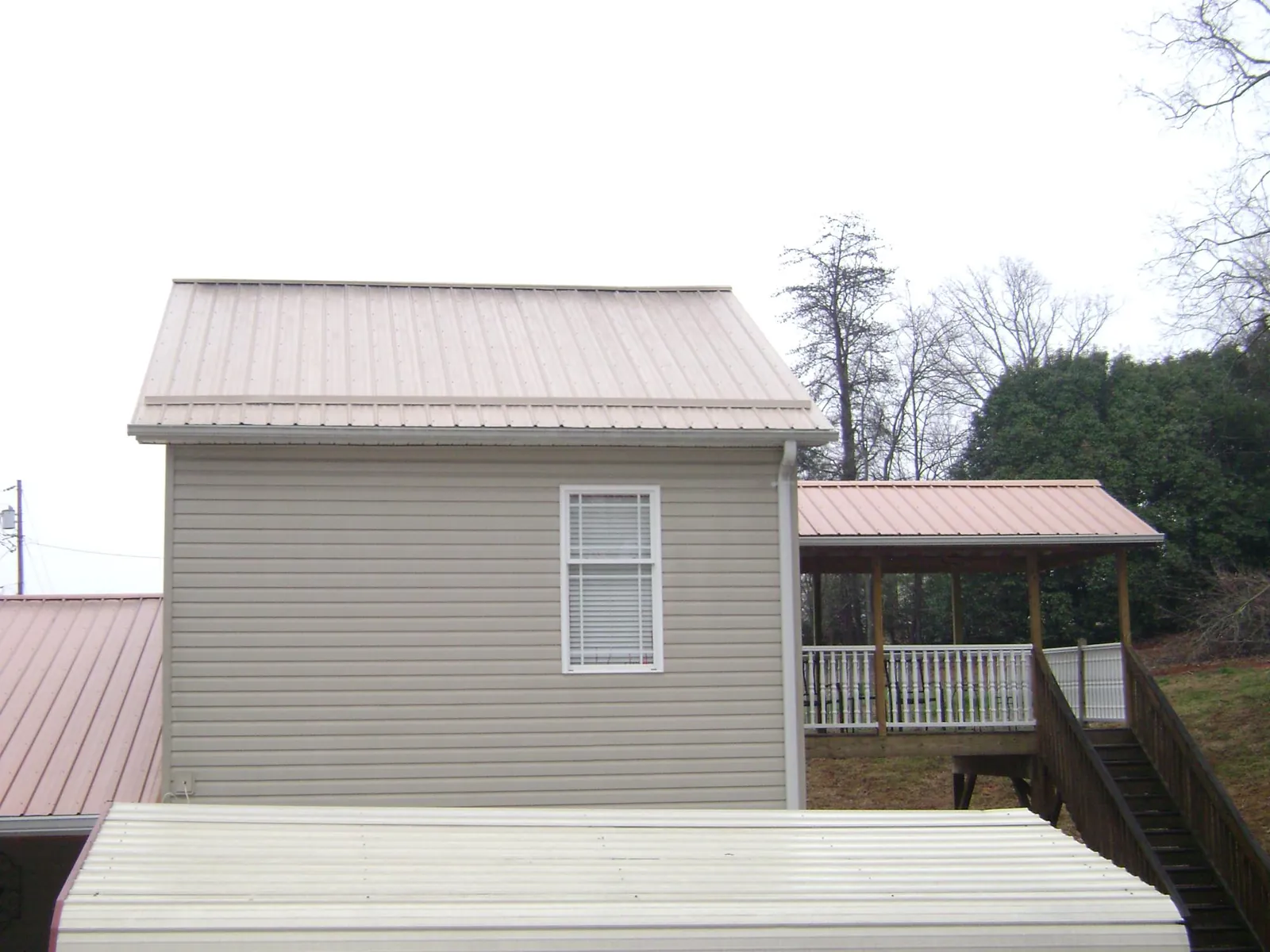Tan metal roofs on a two story addition and attached porch, from a Roof Replacement job in Highmore
